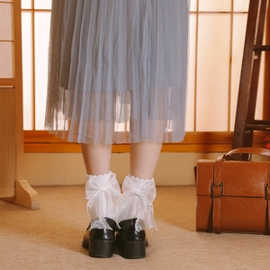 Gros plan de chaussettes Lolita blanches à nœuds en organza et chaussures noires