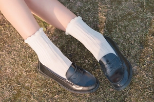 Macro detail of white cotton ribbed mid-calf socks with delicate lace trim edges