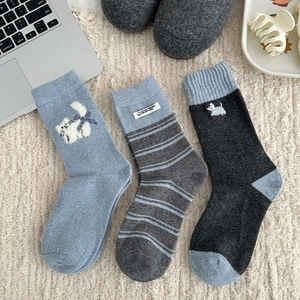 Detail of three pairs of warm wool socks with cartoon cat and stripe patterns on a rug