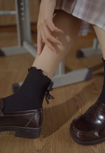 Close-up of black JK style ribbed socks with ruffled edges and satin bow detail