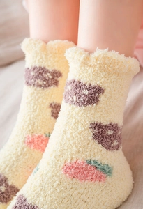 Detailed close-up of thick coral fleece socks featuring strawberry and bear patterns