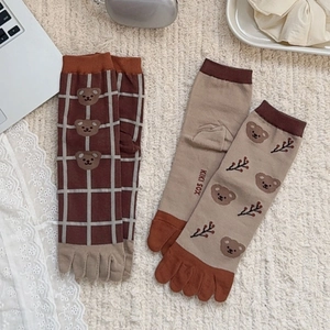 Cute bear and plaid pattern five-finger socks in brown and beige colors on knit background