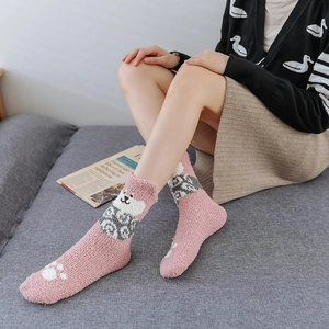 Detail of pink coral fleece socks featuring cute cartoon dog and white paw prints