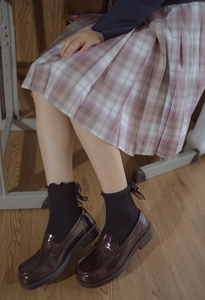 Detail of JK school style pink plaid skirt with black bow ruffled socks and loafers