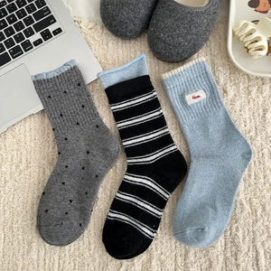 Detailed view of blue-gray wool socks set with stripes and Nice embroidery patch on soft carpet