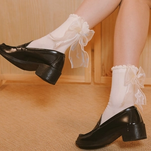 Détail de chaussettes Lolita blanches avec bords à volants et un grand nœud en organza jaune