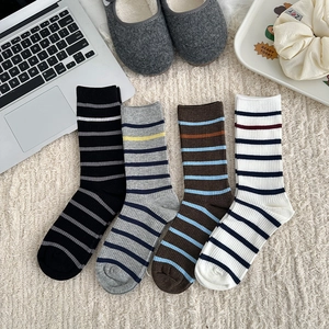Set of four striped mid-calf socks in black, grey, brown and white on a soft rug