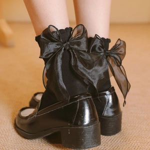 Gros plan de chaussettes noires Lolita ornées d'un grand nœud en organza fin