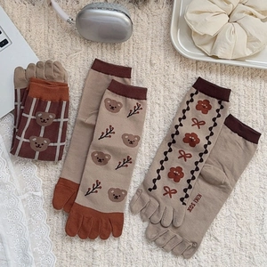 Detail of five-toe socks with cute bear patterns and plaid textures on a soft carpet