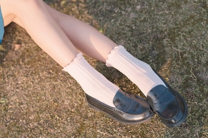 Lace-trimmed knitted socks paired with black loafers on grass in a Japanese JK style