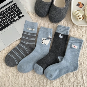 Close-up of four thick wool blend socks in blue-grey tones with cute cartoon embroidery