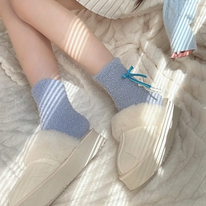 Creamy white plush house shoes with blue bow coral fleece socks in soft sunlight