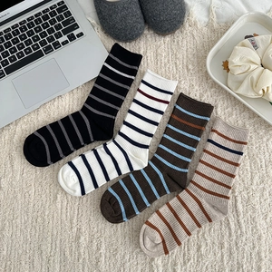 Detail of four pairs of striped knit mid-calf socks in various colors on a plush background