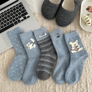 Detail of five pairs of thick wool socks in blue and grey with cute cartoon embroidery