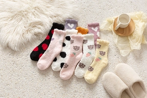 Detailed view of colorful heart and polka dot patterns on plush coral fleece socks