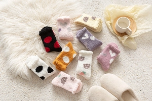 Flat lay of soft coral fleece winter socks in various pastel colors and cute heart patterns