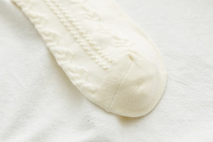 Dettaglio di calze Lolita bianco crema con motivi a trecce e trama con bordo in pizzo