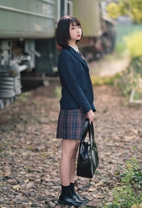Japanese style JK uniform with navy blazer and plaid pleated skirt on railway track