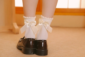 Détail de chaussettes Lolita blanches avec nœud en satin crème et bordure en dentelle