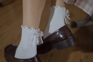 Detail of white Lolita crew socks with ruffled cuffs and delicate chiffon bow accents