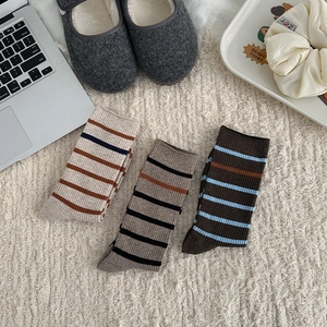 Close-up of vintage striped crew socks in various colors on a cozy home rug