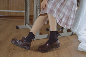 Detail of black JK socks with ruffled edges and satin bow ties styled with loafers
