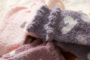 Close-up of soft coral fleece socks in pastel colors with heart patterns and wavy cuffs