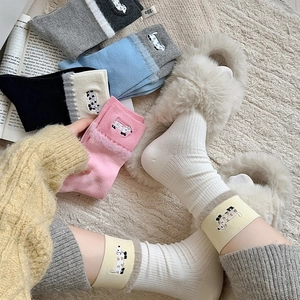 Close-up of knit crew socks with plush trim and cute dog embroidery in various colors