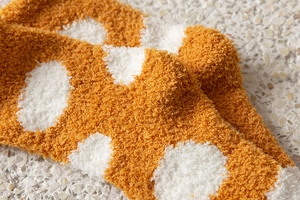Close-up of thick orange coral fleece socks with white polka dots for winter warmth