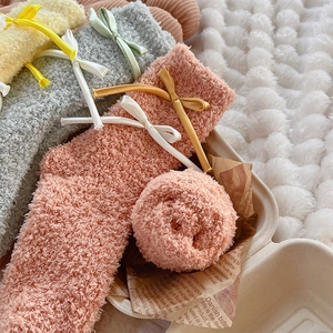 Close-up detail of soft coral fleece socks with elegant silk bow ties in pastel colors