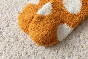 Macro shot of fuzzy orange and white polka dot winter socks with thick coral fleece material