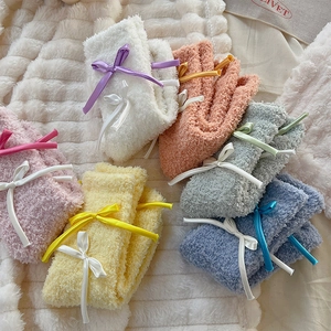 Close-up of fluffy coral fleece socks in pastel colors with satin bow tie details