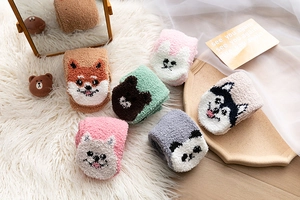 Detail von bunten Korallenfleece-Socken mit süßen Tiermotiven auf weißem Teppich