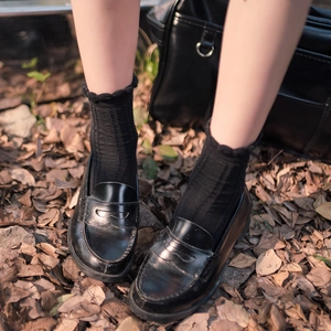 Japanese style black crew socks with ruffle trim and matte leather loafers in autumn setting