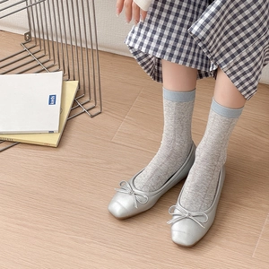 Detail von silbernen Ballerinas mit Schleife und grauen Stricksocken mit blauem Rand