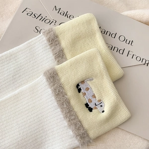 Close-up of white ribbed socks with dalmatian embroidery and brown faux fur trim
