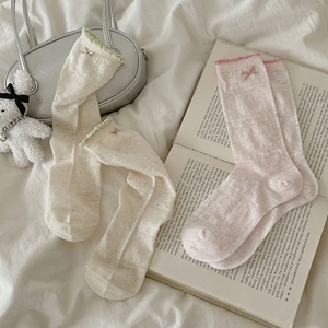 Detail of knit mesh socks with floral eyelets, bow accents and ruffled cuffs in soft pastel