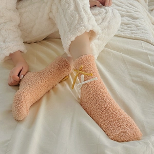 Close-up of soft coral fleece socks in peach pink with ribbon bow details for winter comfort