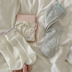 Detail of hollow lace mesh socks with ribbon bows on a soft fabric background