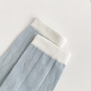 Nahaufnahme hellblauer Baumwollsocken mit Wellenstrickmuster und weißem Rippbündchen