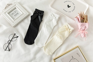 Mise à plat de chaussettes à nœuds noir, blanc et beige avec bords à volants