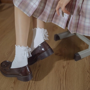 Lolita style white ruffle socks with lace bows paired with dark brown loafers