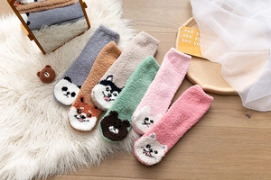 Detail von Korallenvlies-Wintersocken mit niedlichen Tiermustern auf weichem Teppich