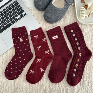Detail of four festive red wool socks with bow embroidery and polka dot patterns