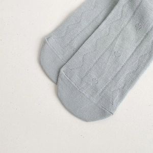 Nahaufnahme von Herzmuster-Stickerei und Rippstrick-Textur auf hellblauen Baumwollsocken