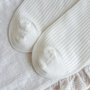 Detail of white ribbed socks featuring delicate lace ruffles and bow embroidery accents