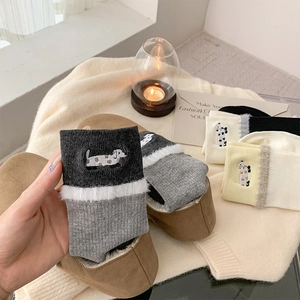 Detail of soft knit socks featuring cute dog embroidery and fluffy white plush trim