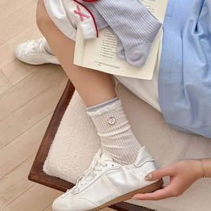 Détail de chaussettes mi-mollet en maille côtelée crème avec broderie pomme rouge