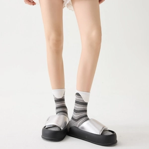 Close-up of silver padded platform slide sandals worn with grey striped crew socks