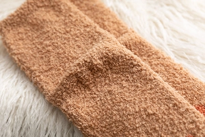 Makroaufnahme flauschiger hellbrauner Korallenvlies-Socken mit weicher Plüschstruktur